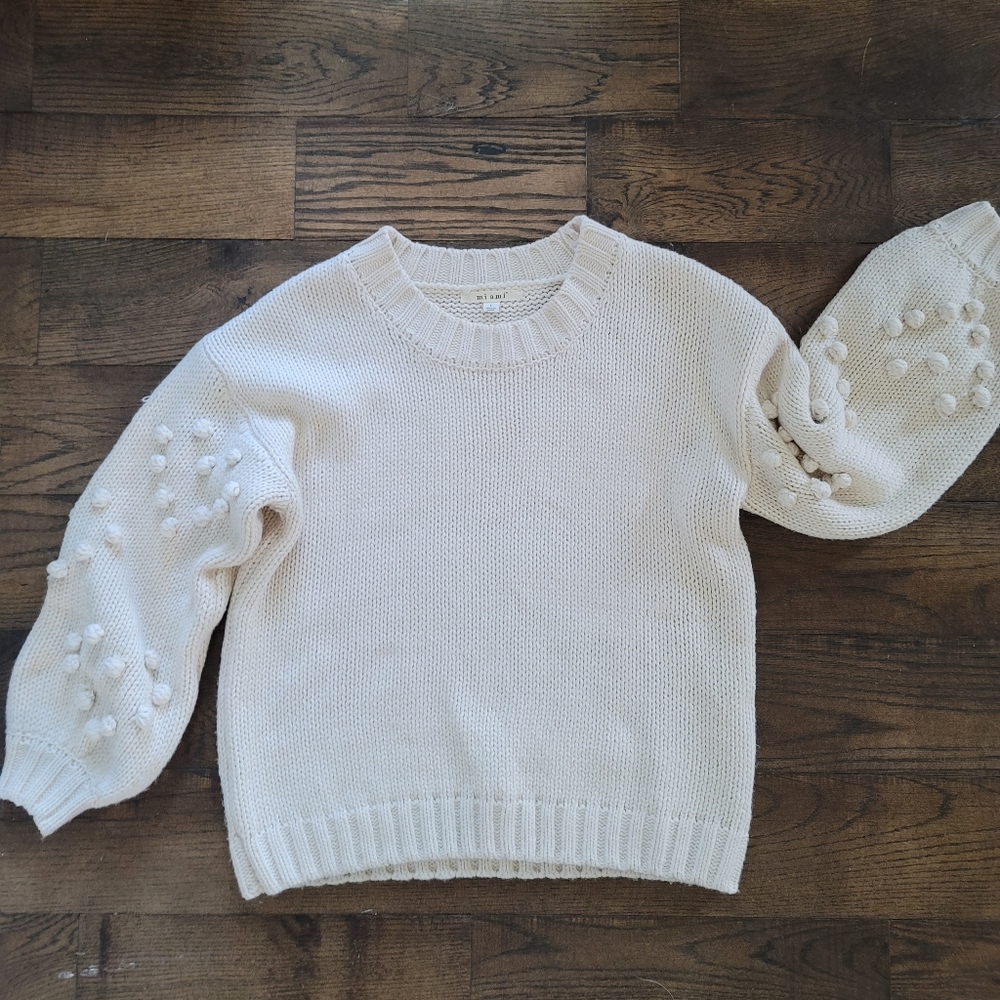 Medium weight Cream sweater with pom pom sleeve detail.